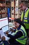 Managers meeting at laptop and computer in distribution warehouse