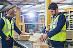 Workers scanning and processing boxes on conveyor belt in distribution warehouse