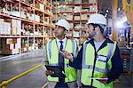 Manger and worker with clipboard and digital tablet talking in distribution warehouse