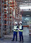 Workers with clipboards looking away in distribution warehouse