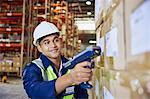 Worker with scanner scanning boxes in distribution warehouse