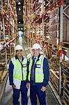 Portrait confident manager and worker in distribution warehouse aisle