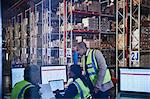 Managers meeting working at laptop and computers in distribution warehouse