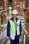 Portrait smiling female worker in distribution warehouse aisle