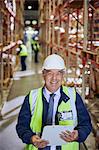Portrait smiling manager with clipboard in distribution warehouse