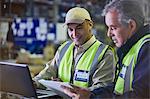 Workers with clipboard and laptop working in distribution warehouse