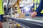 Worker scanning and processing boxes on conveyor belt in distribution warehouse