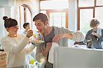 Young woman feeding boyfriend cereal in apartment kitchen