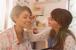 Young women friends applying makeup