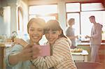 Young women friends roommates hugging taking selfie with camera phone