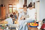 Smiling young couple using digital tablet in kitchen