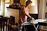 Woman ironing whilst toddler daughter playing on floor