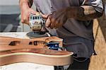 Guitar maker manufacturing guitar in workshop