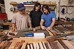 Guitar makers in workshop quality checking guitar necks