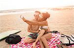 Young couple taking smartphone selfie on Rockaway Beach, New York State, USA