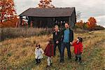 Mid adult family with three daughters holding hands and strolling in rural field