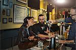 Bartender pouring cocktail for young couple in public house
