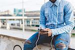 Cropped view of man wearing headphones using smartphone, Milan, Italy