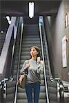 Young woman moving down city escalator