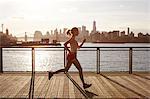 Side view of woman jogging on pier, Manhattan, New York, USA