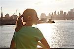 Woman wearing headphones by water, Manhattan, New York, USA