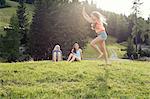 Young woman poised to cartwheel in field, Sattelbergalm, Tirol, Austria