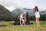 Young woman photographing female friends in Austrian Alps, Sattelbergalm, Tirol, Austria