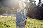 Sunlit portrait of mid adult woman in field, Sattelbergalm, Tirol, Austria