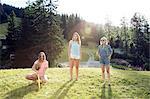 Portrait of three adult female friends standing and crouching in field, Sattelbergalm, Tirol, Austria