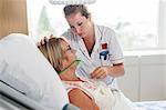 Nurse tending to patient in hospital bed wearing oxygen mask