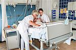 Nurses tending to patient in hospital bed