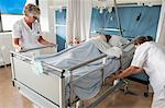 Nurses adjusting patients hospital bed