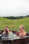Young couple relaxing in rural hot tub with rose wine, Sattelbergalm, Tyrol, Austria