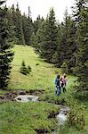 Three female friends walking by forest stream, Sattelbergalm, Tyrol, Austria