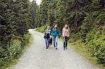 Three female friends walking along forest dirt track, Sattelbergalm, Tyrol, Austria
