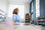 Fashion designer at desk in workshop looking away