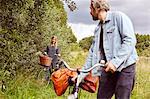 Male cyclist looking back at girlfriend on rural path