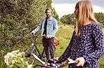 Female cyclist looking back at boyfriend on rural path