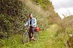 Portrait of mid adult man on bicycle on rural path