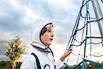 Portrait of boy in astronaut costume gazing by playground climbing frame