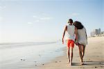 Rear view of romantic young couple strolling on beach, Cape Town, Western Cape, South Africa