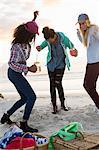 Three young female friends dancing at beach picnic, Cape Town, Western Cape, South Africa