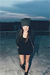Portrait of young woman in knit hat on roof terrace above city at night