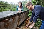 Young couple collecting eggs from chicken coop