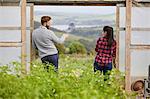 Rear view of couple in polytunnel doorway chatting