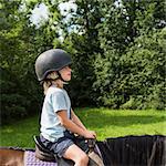 Side view of boy horse riding