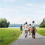 Rear view of parents guiding children on horse, Fuessen, Bavaria, Germany