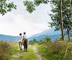 Rear view of mother guiding son riding horse, Fuessen, Bavaria, Germany