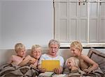 Grandmother in bed with grandsons using digital tablet