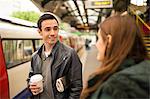 Couple on railway platform face to face smiling